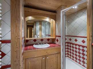 This charming bathroom features a rustic wooden vanity with a white basin sink, complemented by a large arched mirror.