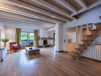 Experience rustic charm in this spacious living area, featuring exposed wooden beams on the ceiling and a cozy fireplace.