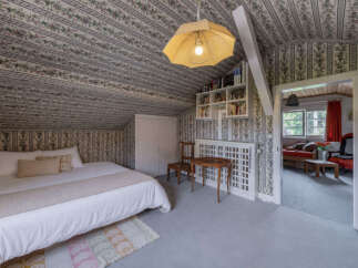 Step into a charming attic bedroom featuring a cozy bed adorned with crisp white linens and a textured throw.