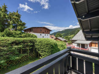 Enjoy breathtaking mountain views from this charming balcony, surrounded by lush greenery and mature trees.