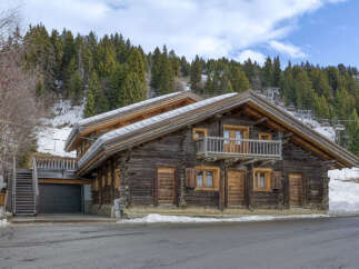 Experience the charm of this rustic log cabin nestled in a snowy mountain landscape.