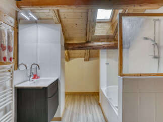 Experience rustic charm in this bathroom featuring exposed wooden beams and a skylight that floods the space with natural light.
