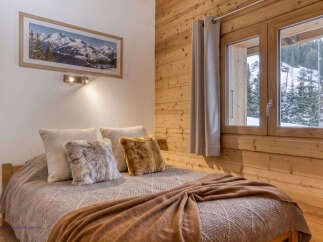 Experience cozy mountain living in this charming bedroom, featuring a comfortable bed adorned with plush pillows and a warm, textured throw blanket.