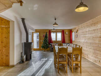 Experience cozy living in this charming mountain retreat, featuring a rustic dining area with a large wooden table and chairs, perfect for family gatherings.