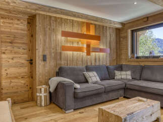 Experience rustic charm in this cozy living room, featuring warm wood paneling throughout and a comfortable L-shaped sectional sofa.