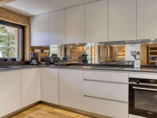 Experience modern living in this sleek kitchen, featuring clean white cabinetry and a reflective backsplash that amplifies the natural light.