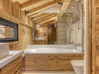 Experience rustic luxury in this stunning bathroom, featuring warm wooden paneling throughout and a spacious bathtub perfect for relaxation.
