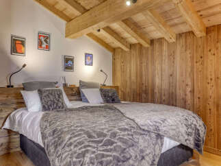 Experience rustic charm in this cozy bedroom, featuring a plush bed adorned with luxurious grey bedding and accent pillows.