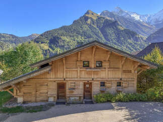 Experience the charm of this traditional wooden chalet nestled against a breathtaking mountain backdrop.