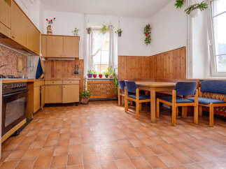 This charming kitchen and dining area features warm wooden cabinetry and paneling, complemented by a practical tiled floor.