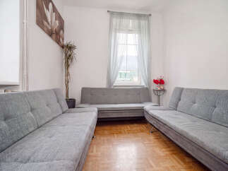 Step into this inviting living room, featuring three comfortable grey sofas arranged to maximize conversation and relaxation.