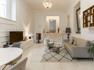 Step into this elegant and spacious living area, featuring a plush beige sofa and a cozy armchair perfect for relaxation.