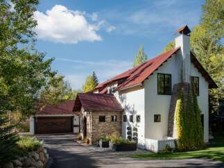 Discover this stunning mountain home featuring a striking red metal roof and a charming stone-accented entryway.