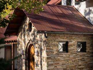 Discover this charming home featuring a rustic stone facade and a distinctive corrugated metal roof, creating a unique architectural statement.