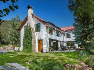 Experience luxury living in this stunning mountain home, featuring a charming stone and stucco exterior with a rustic copper roof.