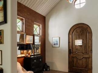 Step into a grand entryway featuring a stunning arched wooden door and a unique, multi-colored glass chandelier.