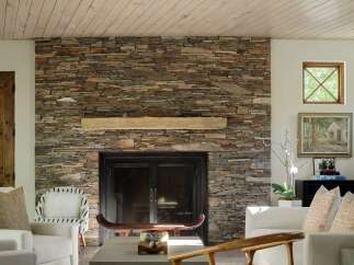 This living room boasts a stunning floor-to-ceiling stacked stone fireplace, creating a rustic and inviting focal point.