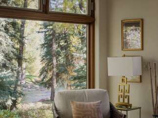 Experience serene living with this stunning view of a natural landscape, complete with a flowing stream and lush trees, visible through a large, well-appointed window.