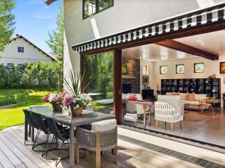 Enjoy seamless indoor-outdoor living with this stunning property, featuring a spacious deck with a glass-top dining table and comfortable seating, perfect for al fresco dining.