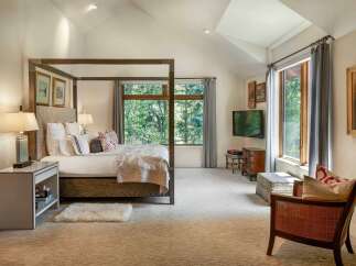 Experience luxury in this master bedroom featuring a grand four-poster bed adorned with plush pillows and a decorative quilt.