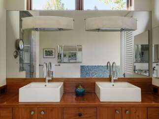 This modern bathroom features a double vanity with two square vessel sinks atop a rich wooden countertop.