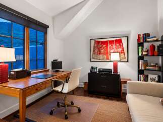 This home office features a spacious wooden desk with a computer, telephone, and printer, perfect for productivity.