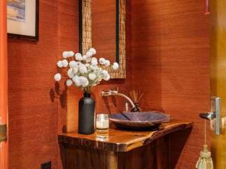 This powder room features a striking live-edge wood vanity with a unique purple mosaic sink and a modern brushed nickel faucet.