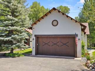 This charming property features a rustic wooden garage door with a decorative 'X' pattern, complemented by a classic American flag.