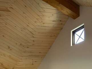Experience the warmth and natural beauty of this home's interior, featuring a stunning vaulted ceiling with exposed wooden beams and intricate wood planking.