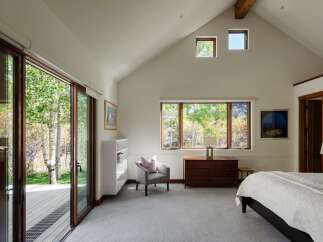 Experience serene living in this spacious bedroom, featuring a vaulted ceiling with exposed wooden beams and ample natural light.