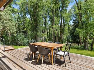 Enjoy al fresco dining on this expansive wooden deck, perfect for entertaining guests amidst a serene natural setting.