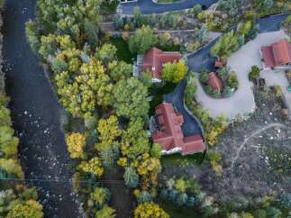 Experience luxury living with this stunning aerial view of a multi-building estate nestled beside a flowing river.