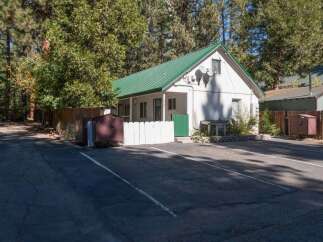 Discover this charming white cottage featuring a vibrant green metal roof, perfect for a cozy retreat.