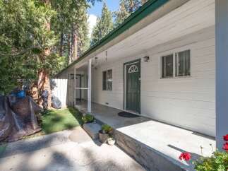 Discover this charming home featuring a welcoming covered porch with a classic green front door and a decorative arched window.