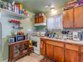 This charming kitchen features a white gas range with a microwave and toaster oven conveniently placed on a wooden cabinet.