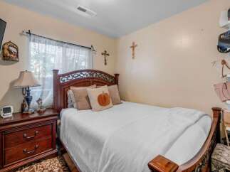 This cozy bedroom features a beautiful dark wood bed frame with ornate detailing, complemented by plush pillows and a white quilted comforter.