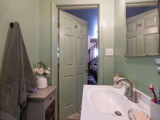This bathroom features a light green painted door that opens to reveal a staircase and living area.