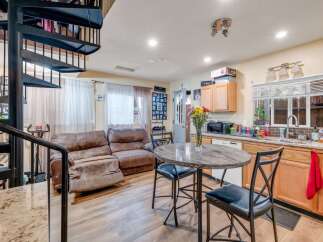This charming open-concept living space features a comfortable brown leather sectional sofa, perfect for relaxing.