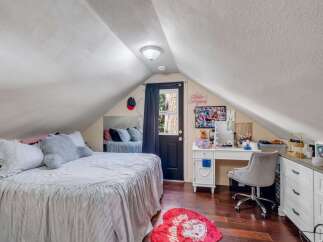 This charming attic bedroom offers a cozy retreat with its sloped ceilings and ample natural light.