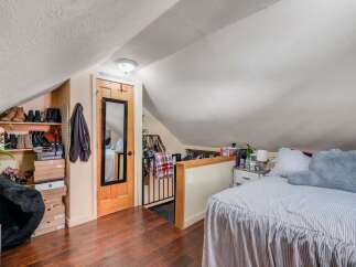 Discover this charming attic bedroom, featuring a cozy sleeping area with a striped comforter and plush pillows.