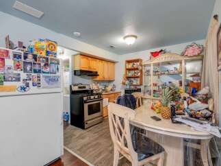 This charming kitchen offers ample storage with its wooden cabinets and a spacious refrigerator adorned with family photos and accolades.