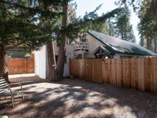 Enjoy the serene backyard of this property, complete with a sturdy wooden fence and mature pine trees providing ample shade.