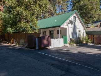 Discover this charming property featuring a durable green metal roof and a crisp white exterior, nestled amongst mature trees.