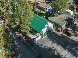 Discover this charming property featuring a bright white exterior and a striking green metal roof, offering a modern and durable aesthetic.
