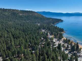 Discover this stunning lakeside property nestled amidst a dense forest of pine trees, offering breathtaking views of the crystal-clear blue lake.