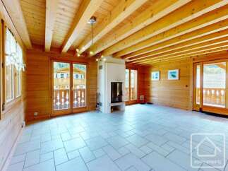 Experience the charm of this rustic living room, featuring exposed wooden beams on the ceiling and warm wood-paneled walls.