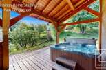 Experience ultimate relaxation with this luxurious hot tub, perfectly situated on a wooden deck under a charming covered patio.