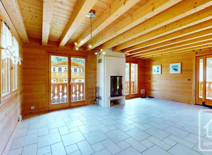 Experience rustic charm in this beautifully appointed living space, featuring warm wooden walls and exposed beams that create a cozy alpine ambiance.