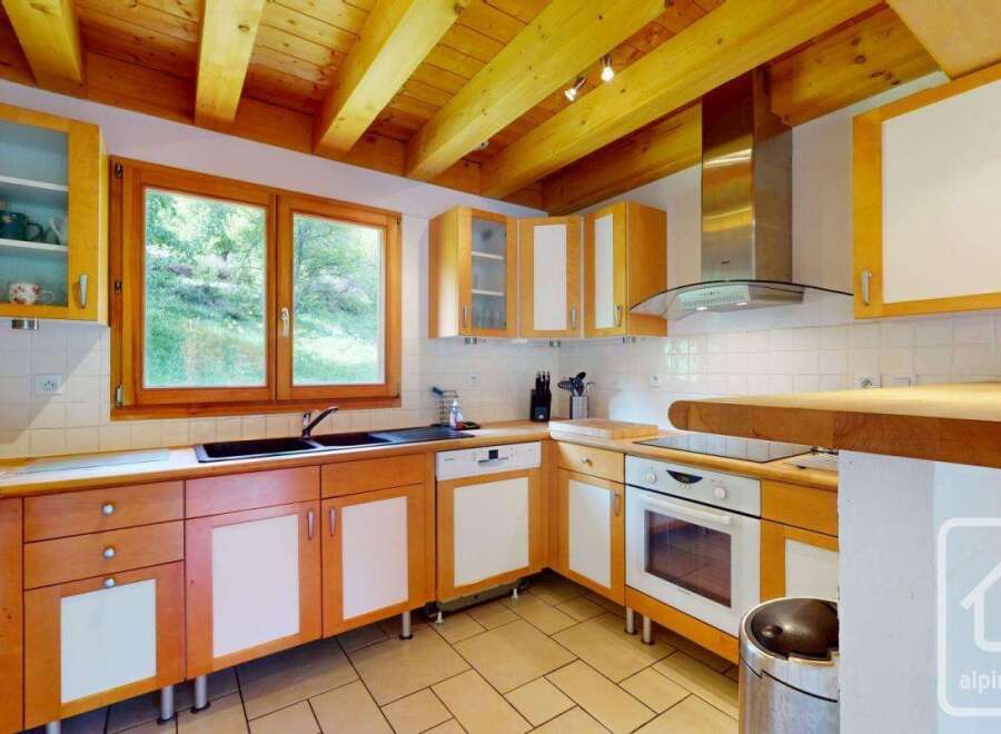 This charming kitchen features warm wooden cabinetry with white accents, complemented by a spacious wooden countertop.
