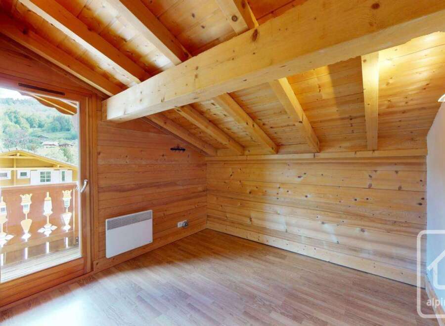 Experience rustic charm in this attic room, featuring exposed wooden beams and paneling that create a warm, inviting atmosphere.